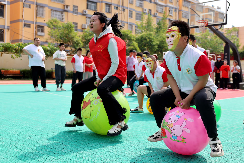 2024年5月17日，在山東省棗莊市市中區(qū)特殊教育中心，青年志愿者與智力障礙學(xué)生一起做游戲。新華社發(fā)（孫中喆攝）